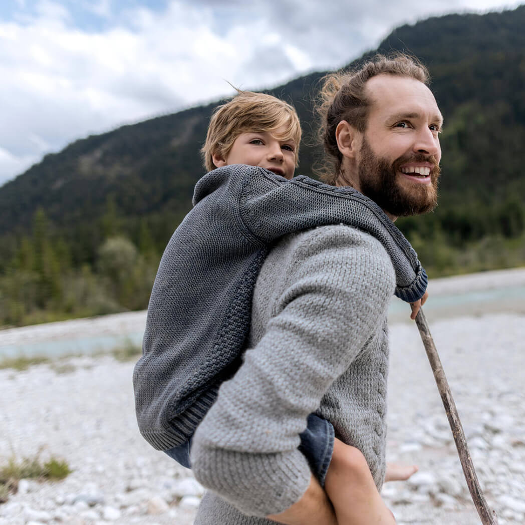 A man carries a child along a river